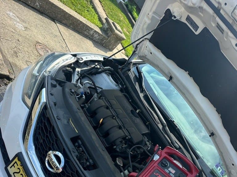 Road Heroes booster pack connected under an open hood for jump start service