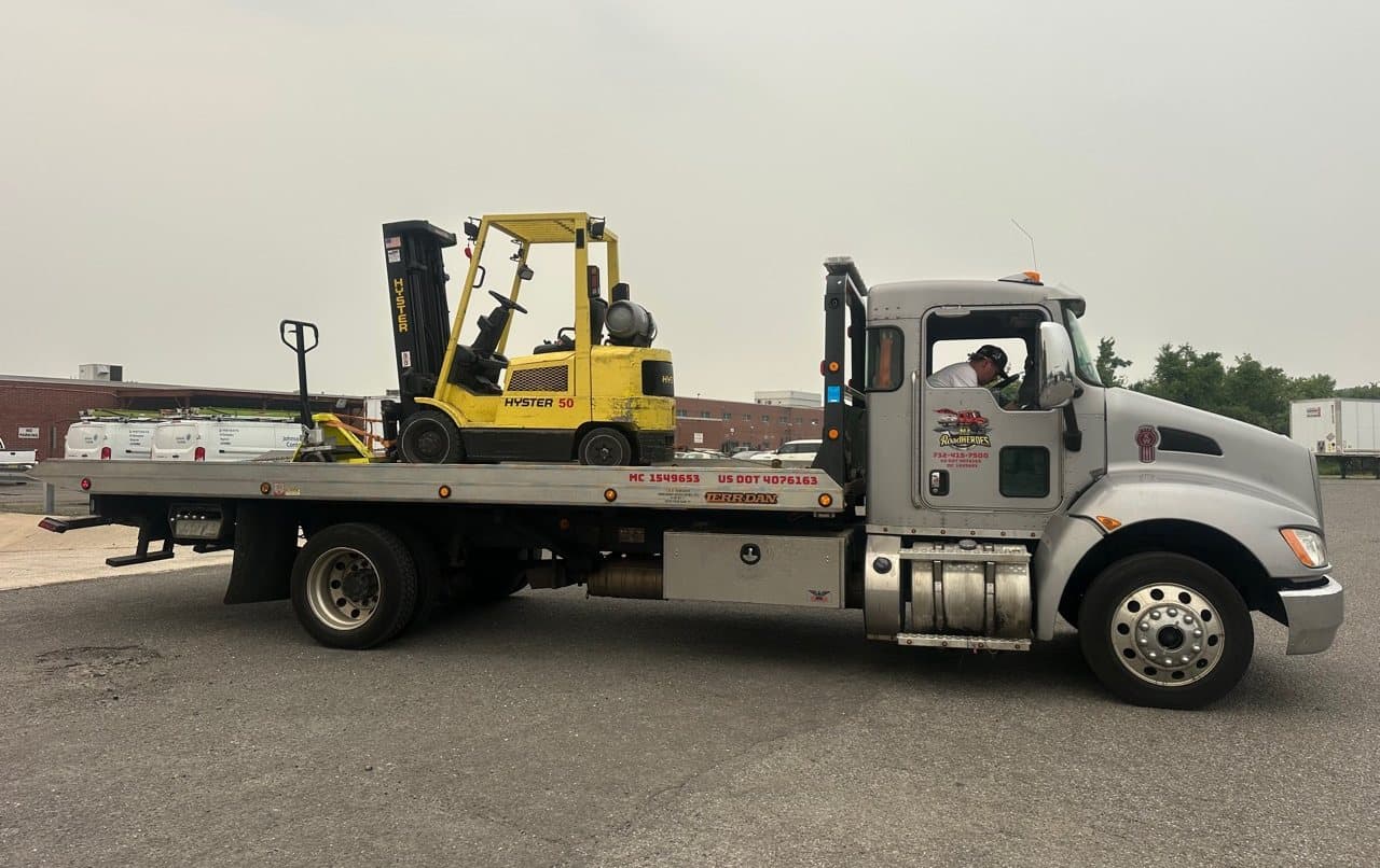 Road Heroes flatbed truck hauling a forklift for equipment transport