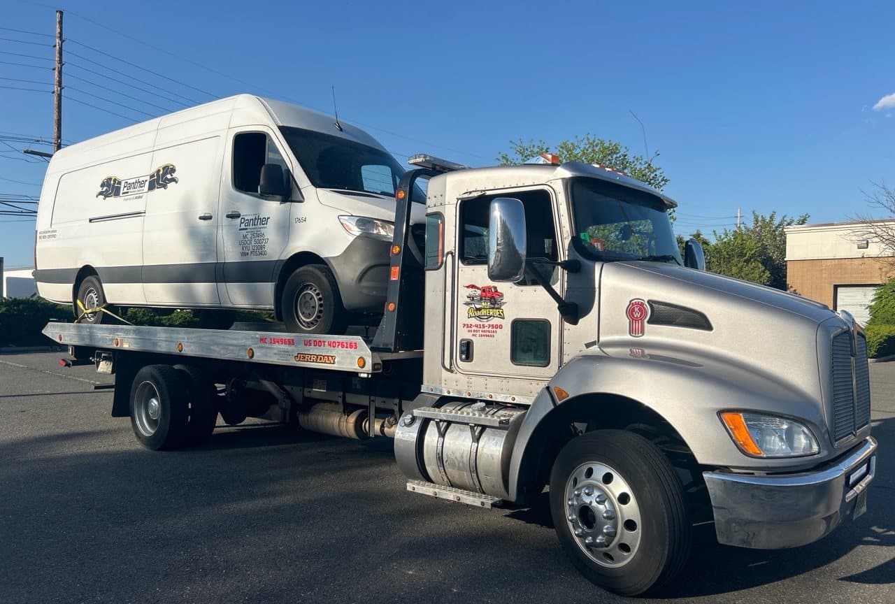 Road Heroes flatbed truck transporting a commercial logistics van