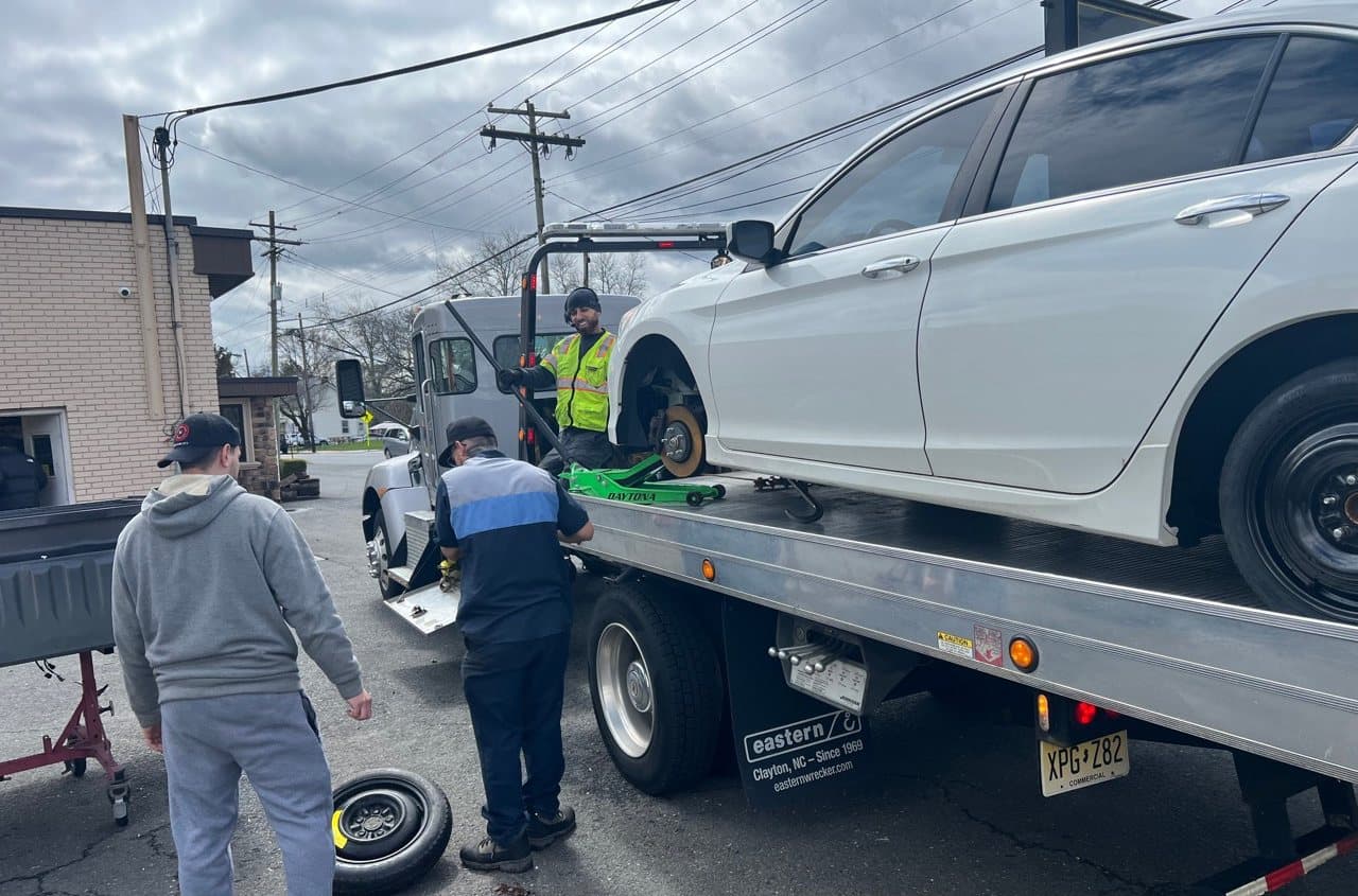 Road Heroes roadside wheel service with a spare tire beside a flatbed truck