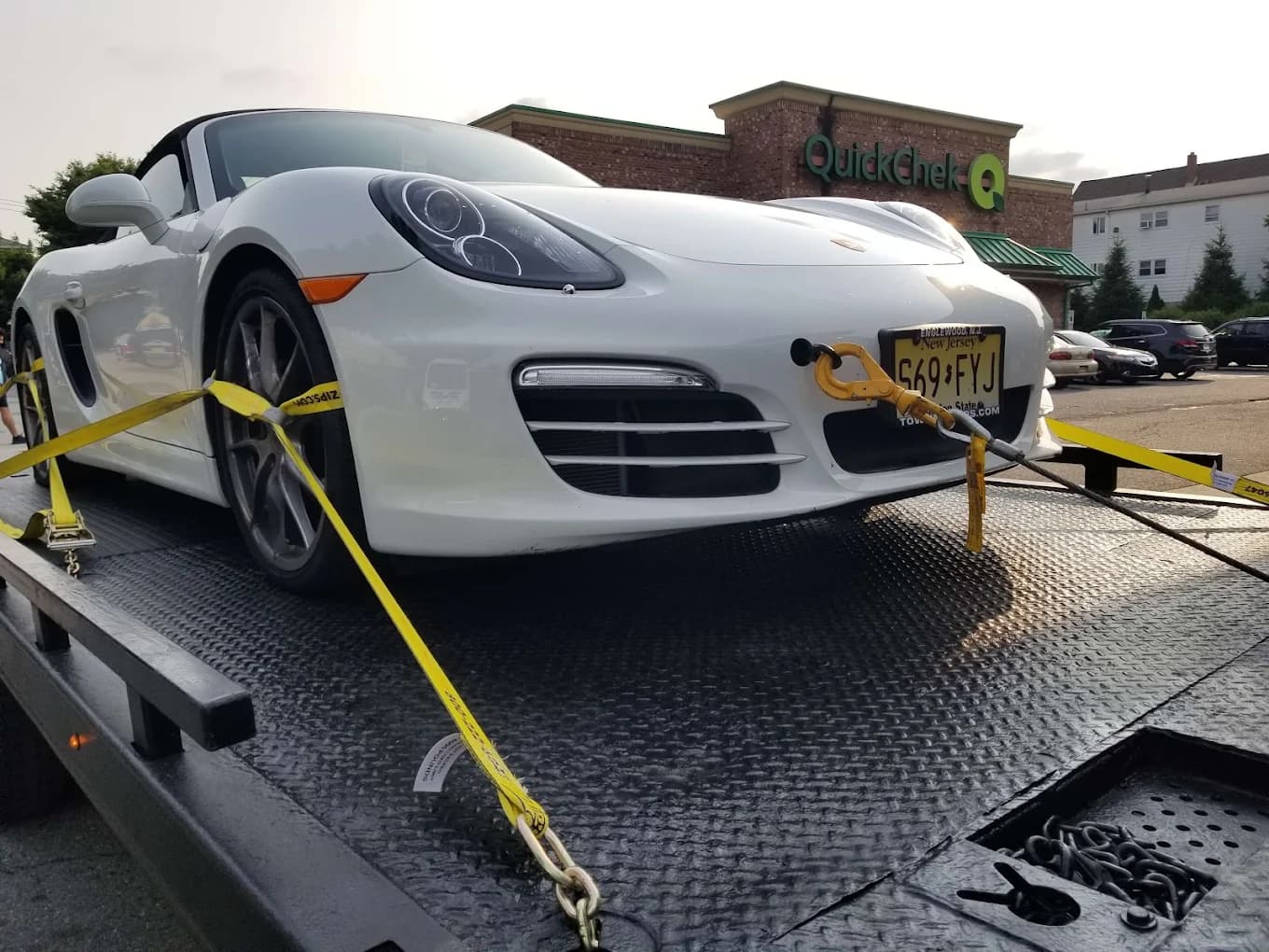 White Porsche Boxster securely strapped on flatbed for towing
